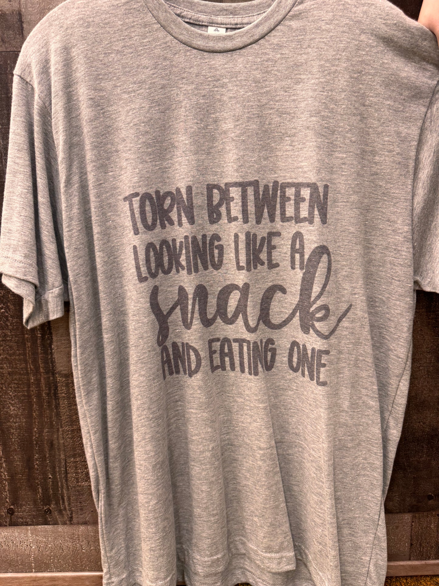 Torn Between Looking Like a Snack Tee